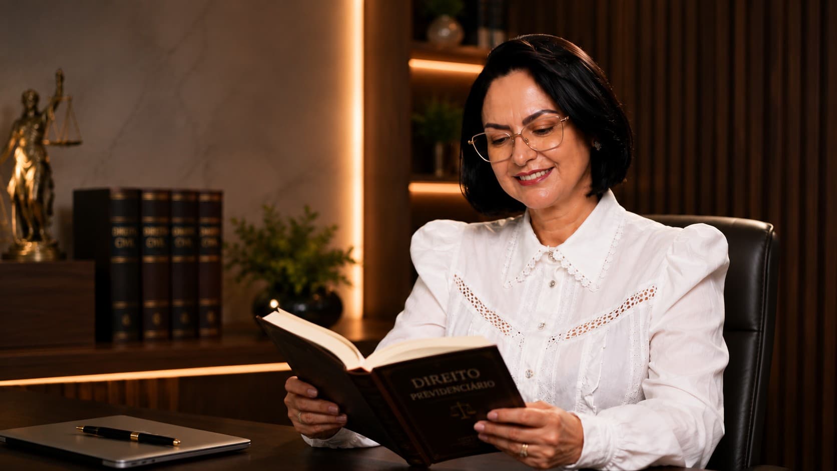 Dra. Sheila Araújo lendo um livro de Direito Previdenciário em seu escritório